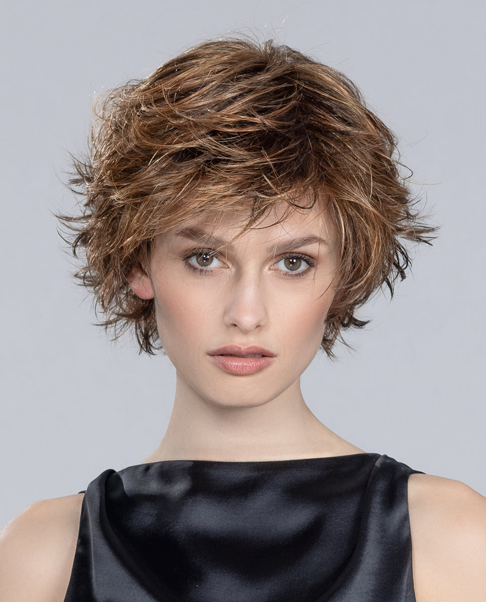 A woman wearing the Date Large short wig with a modern layered and tapered cut in a tousled style by Ellen Wille.