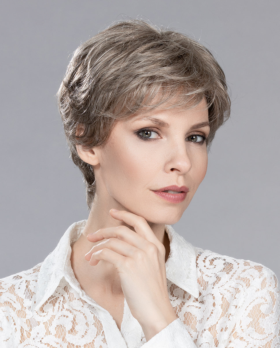 A woman wearing the Ellen Wille Apart Mono wig, showcasing its soft waves, crown volume, and realistic monofilament parting.