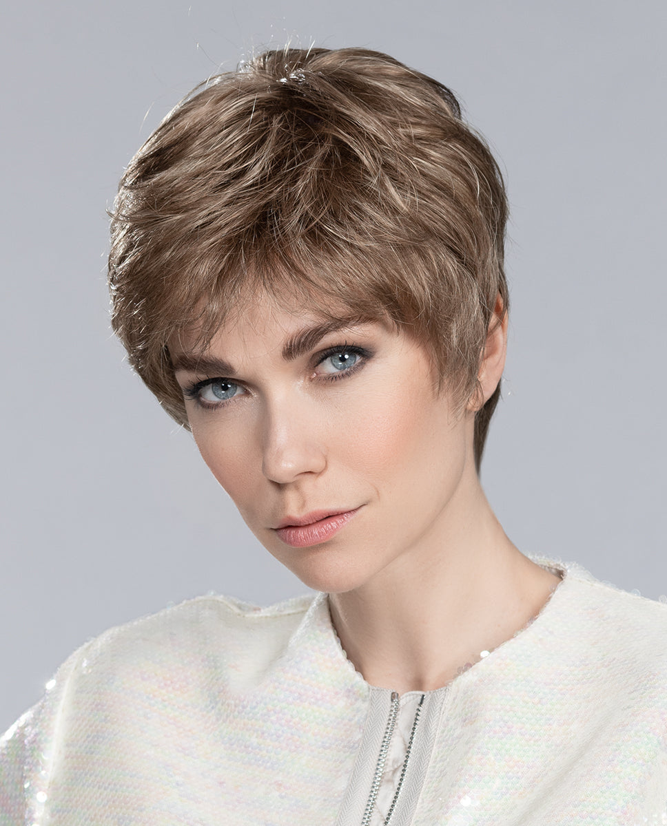 A woman modeling the Ellen Wille Carol short wig with layered hair and a soft tapered fringe in a natural style.