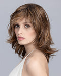 A woman modeling the Ellen Wille Casino Mono Part wig, highlighting its mid-length tapered layers and realistic monofilament parting line.
