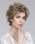 Front view of a woman wearing the Ellen Wille City wig, showcasing its soft voluminous curls and elegant wispy fringe.