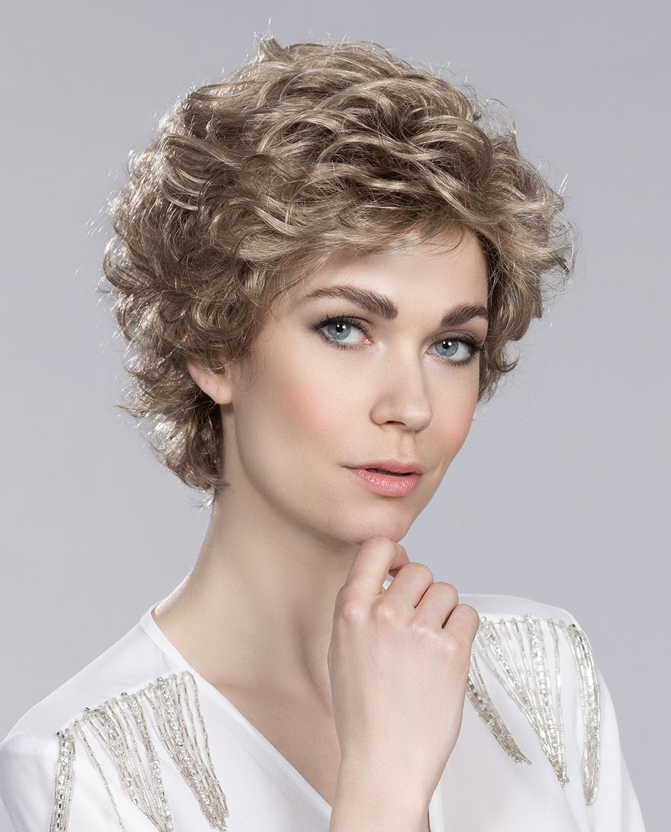 Front view of a woman wearing the Ellen Wille City wig, showcasing its soft voluminous curls and elegant wispy fringe.