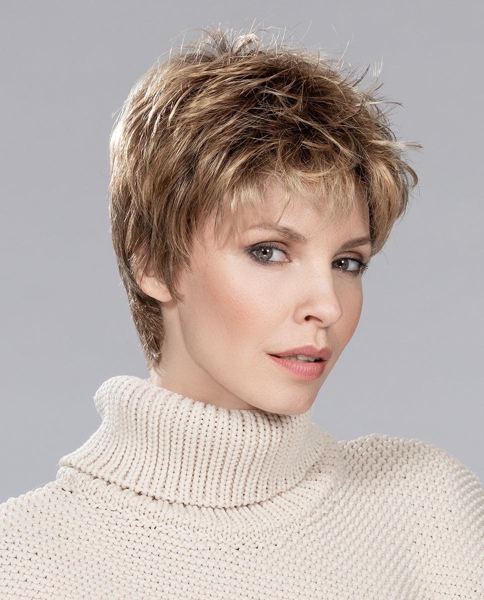 A woman modeling the Ellen Wille Coco short wig, showcasing its voluminous tapered pixie cut and effortless texturized styling.