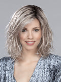 A woman modeling the Ellen Wille Destiny Mono Part wig, showcasing its elegant mid-length layered bob cut and realistic monofilament parting line.