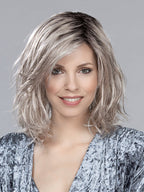 A woman modeling the Ellen Wille Destiny Mono Part wig, showcasing its elegant mid-length layered bob cut and realistic monofilament parting line.
