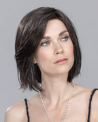 A woman modeling the Ellen Wille Elite Small Mono Part wig, highlighting its petite cap fit, sleek mid-length bob cut, and versatile extended lace front hairline.