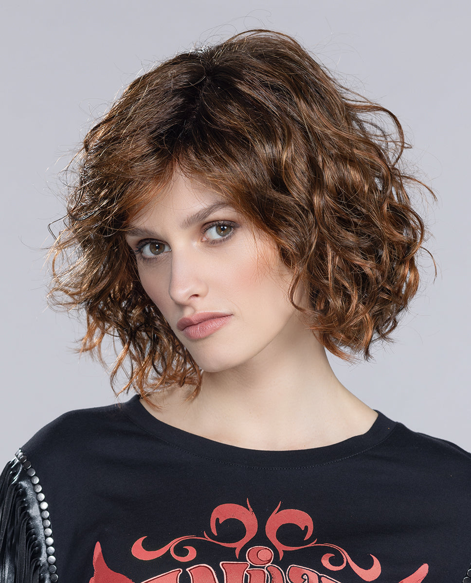 A woman modeling the Ellen Wille Girl Mono Part wig, showcasing its textured mid-length waves, natural parting line, and voluminous, bold silhouette.