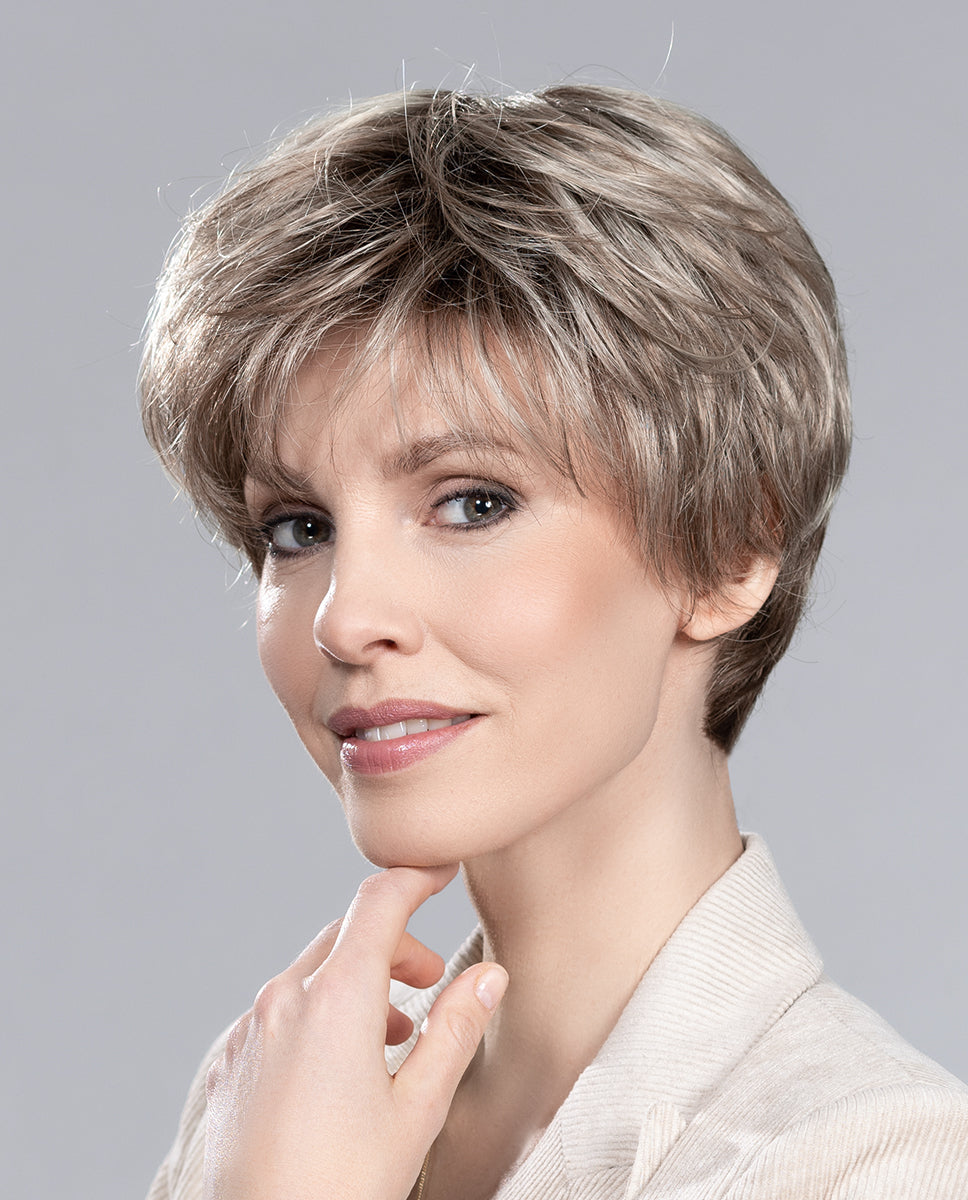 A woman modeling the Ellen Wille Gold short pixie wig, highlighting its soft layers, elegant silhouette, and natural volume at the monofilament crown.