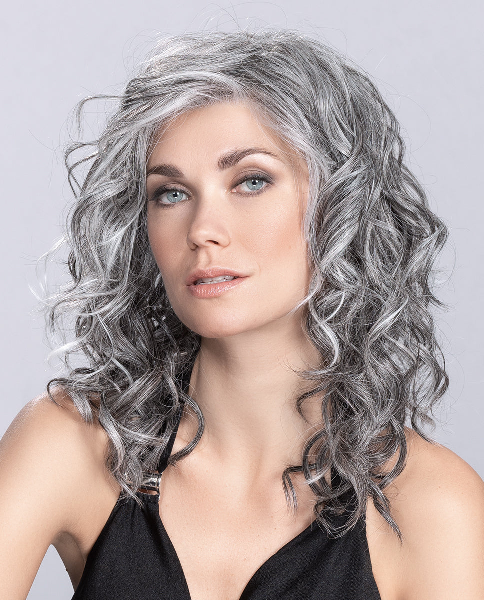 A woman modeling the long, flowing Ellen Wille Heaven Mono Part wig, showcasing its ultra-natural parting line, polished length, and feminine layers.