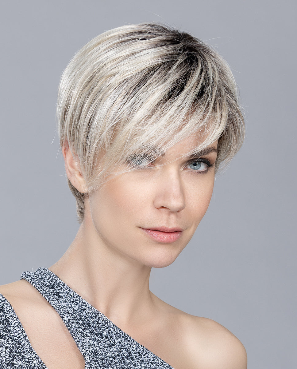 A woman modeling the short Ellen Wille Jump Mono wig, showcasing its modern asymmetrical side volume and seamless monofilament top parting.