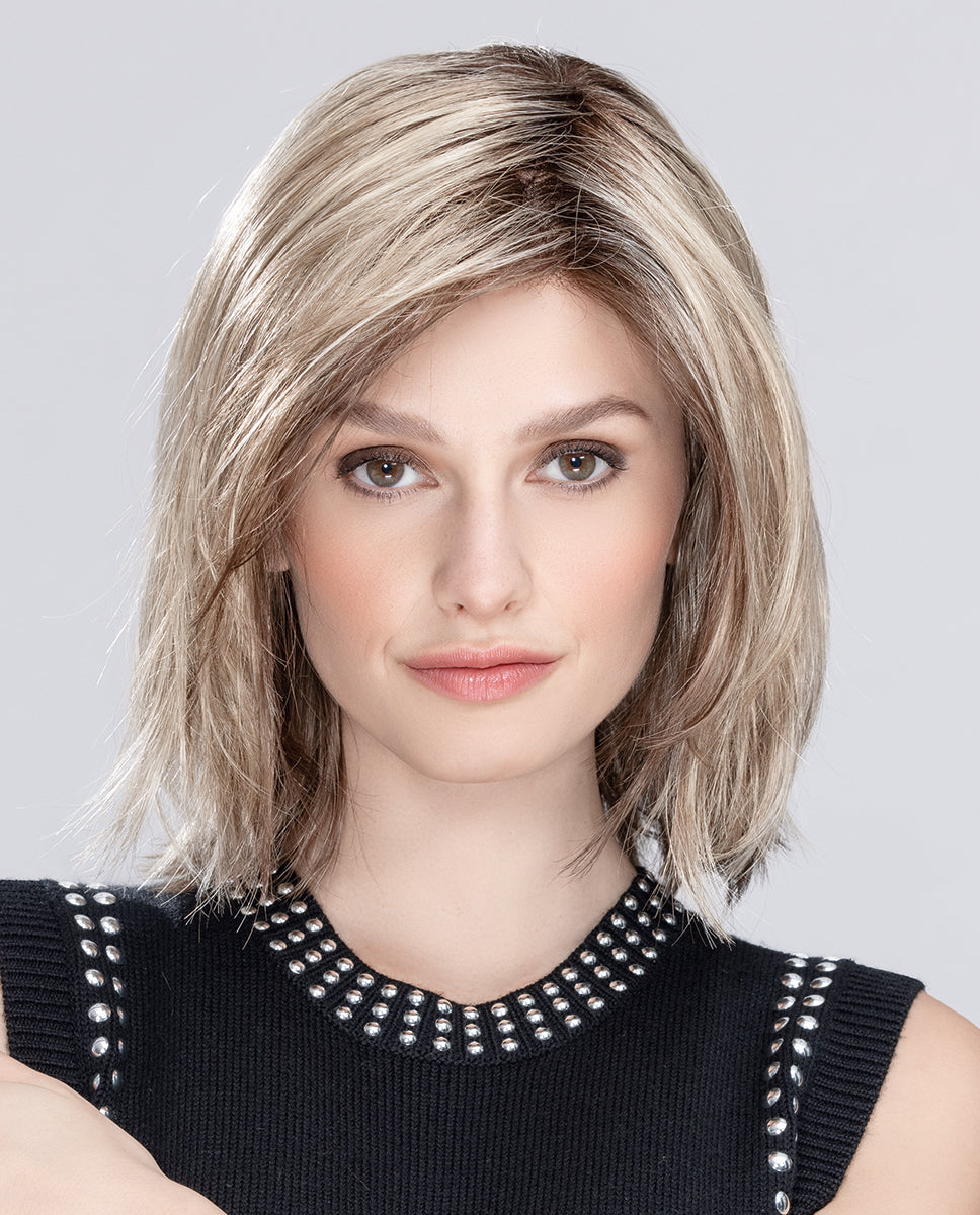 A woman modeling the upgraded shoulder-length Ellen Wille Limit Mono Part wig, showcasing its face-framing layered fringe and invisible extended lace front hairline.