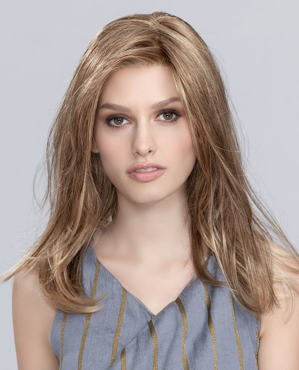 A woman modeling the long Ellen Wille Miley Small Mono wig, showcasing its wispy fringe, tapered ends, secure petite cap fit, and natural monofilament top.