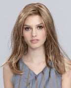 A woman modeling the long Ellen Wille Miley Small Mono wig, showcasing its wispy fringe, tapered ends, secure petite cap fit, and natural monofilament top.