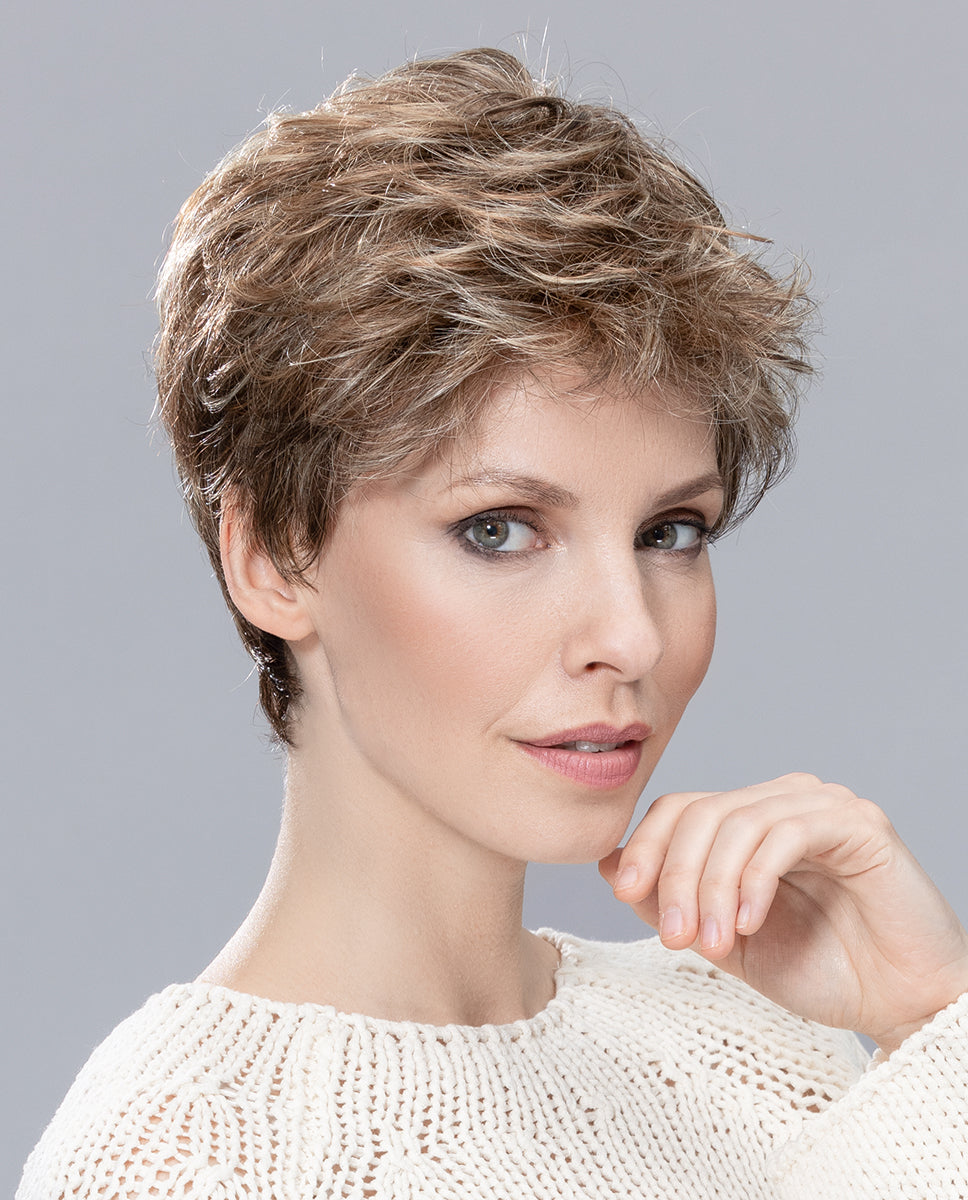 A woman modeling the Ellen Wille Sun Mono wig, showcasing its voluminous tapered crown layers, short cropped length, and natural monofilament top.