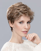 A woman modeling the Ellen Wille Sun Mono wig, showcasing its voluminous tapered crown layers, short cropped length, and natural monofilament top.