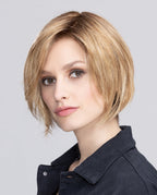 Side profile of a woman modeling the Ellen Wille Talia Mono wig, showcasing its short contemporary bob cut, clean tapered nape, and sweeping side fringe.